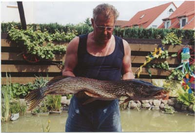 Heinz Gerloff mit Fisch vor seinem Gartenteich